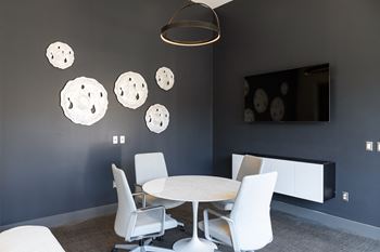a room with a table and chairs and a television on the wall